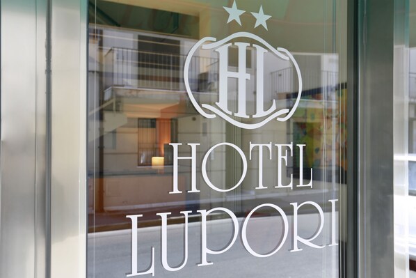 A hotel sign with the name "HOTEL LUPORI" and a logo with three stars. - Hotel Lupori (Viareggio)