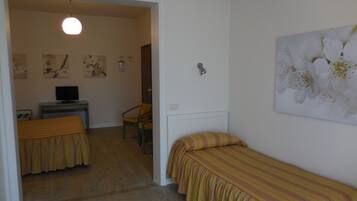 A bedroom with a bed, a chair, a desk with a computer, and a painting on the wall.