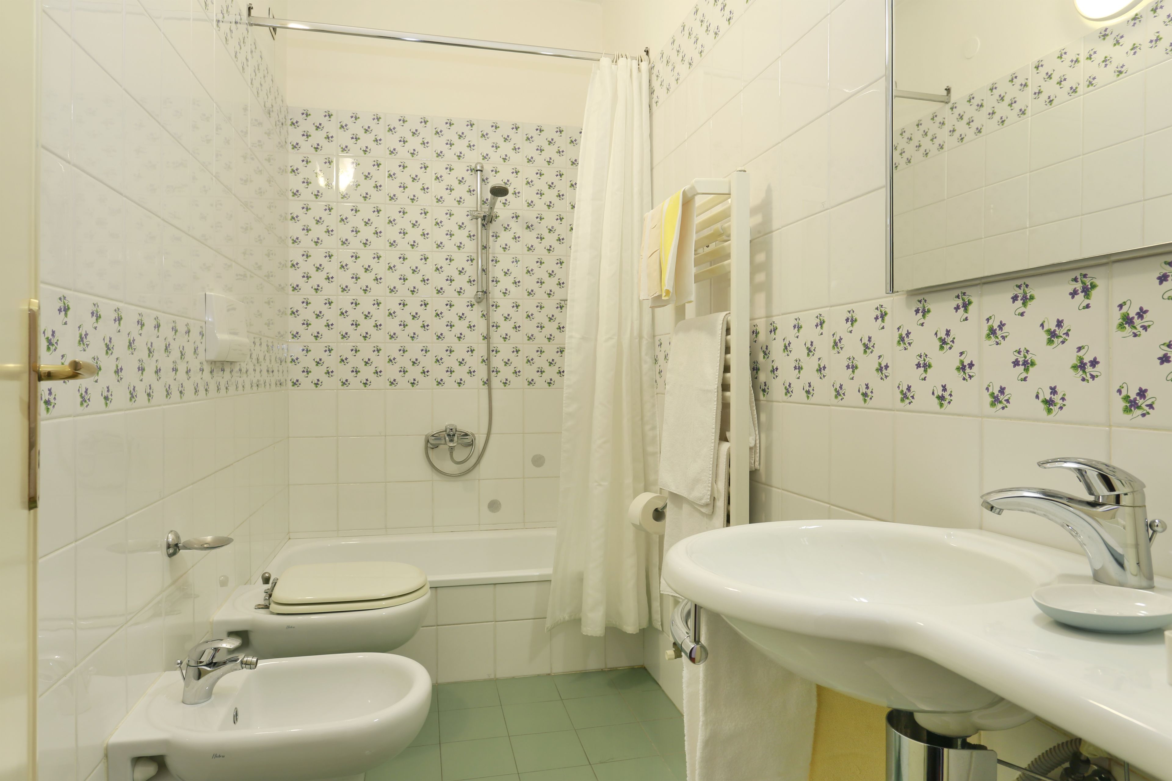 A bathroom with a toilet, bidet, bathtub, and sink.