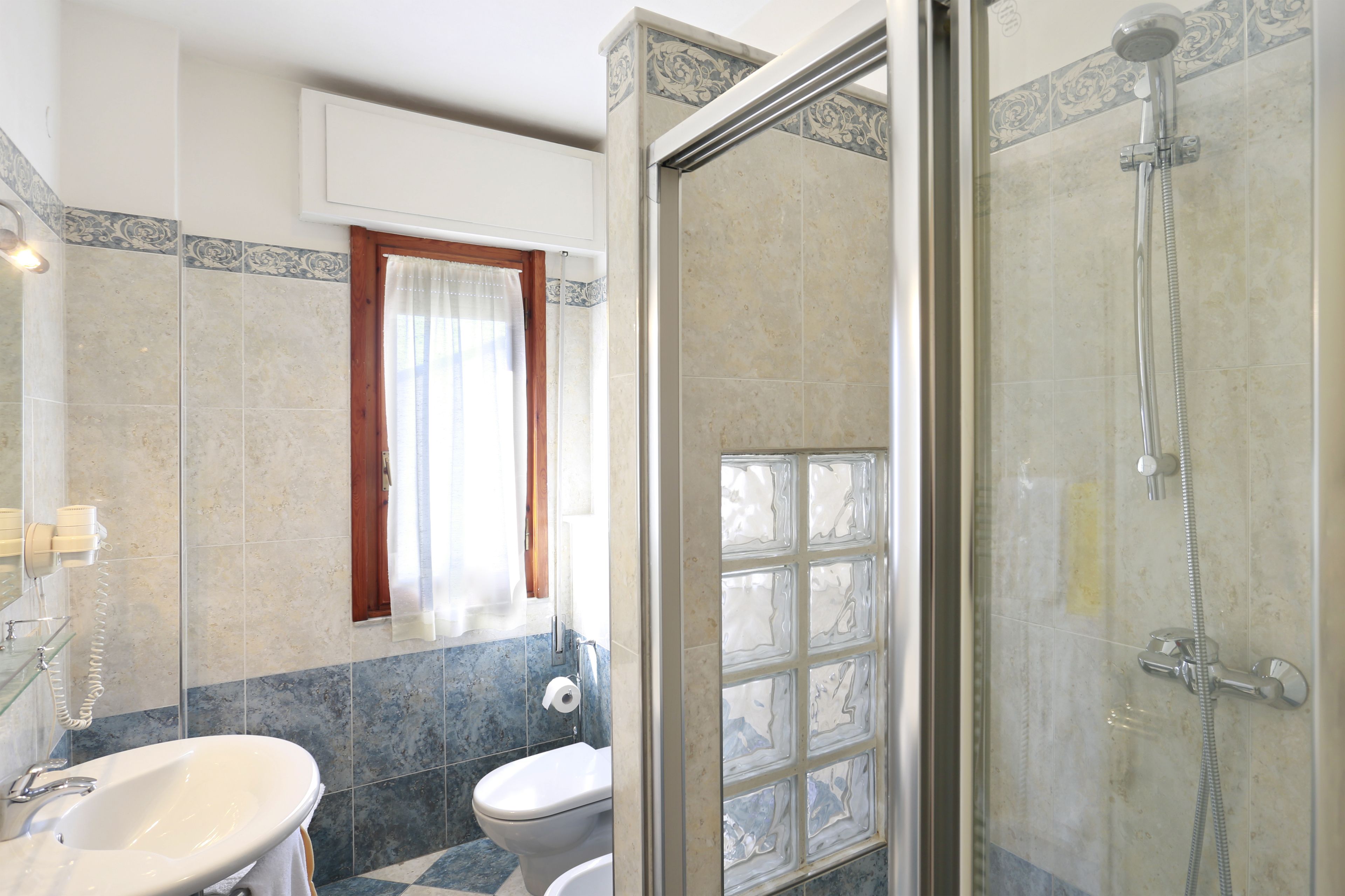 Un baño con ducha de vidrio, lavamanos e inodoro.