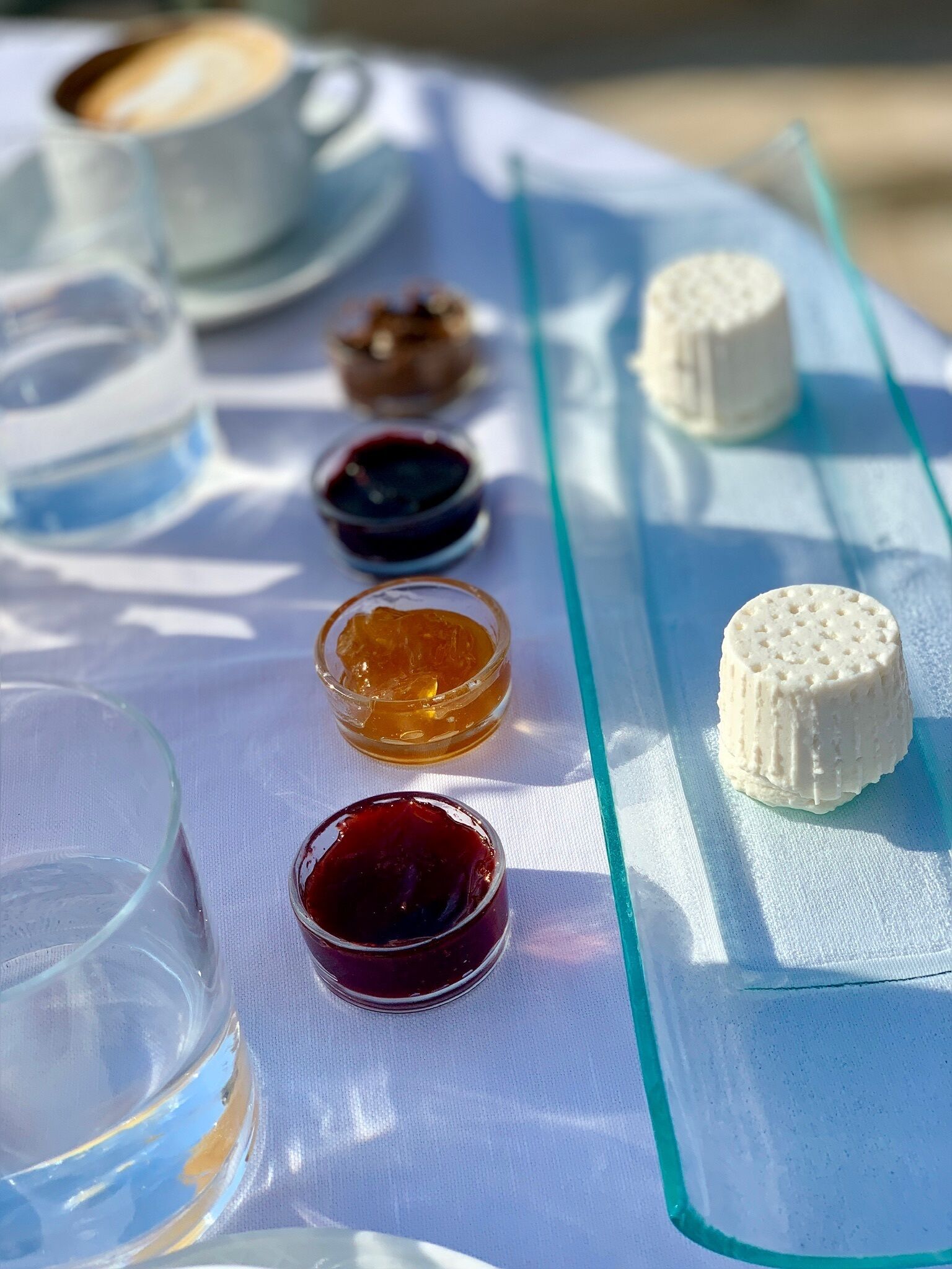 A table with various food items and drinks, including a cup of coffee, a glass of water, and small bowls of condiments.