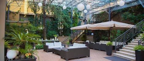 An indoor garden with a glass ceiling, seating areas, and a staircase.