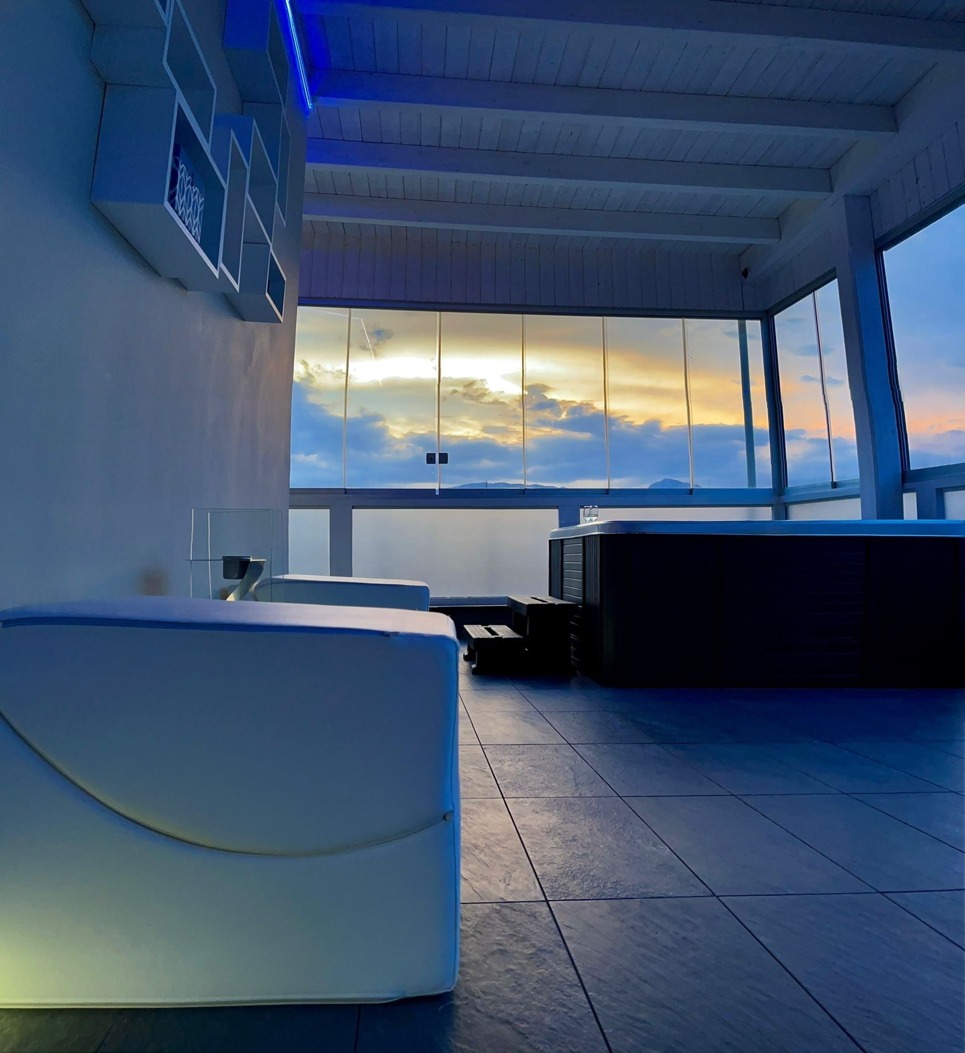 A modern interior with a large window offering a view of the sunset.