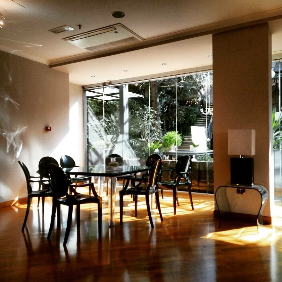 Une salle de conférence avec une table et des chaises en verre, de grandes fenêtres et une plante en pot.