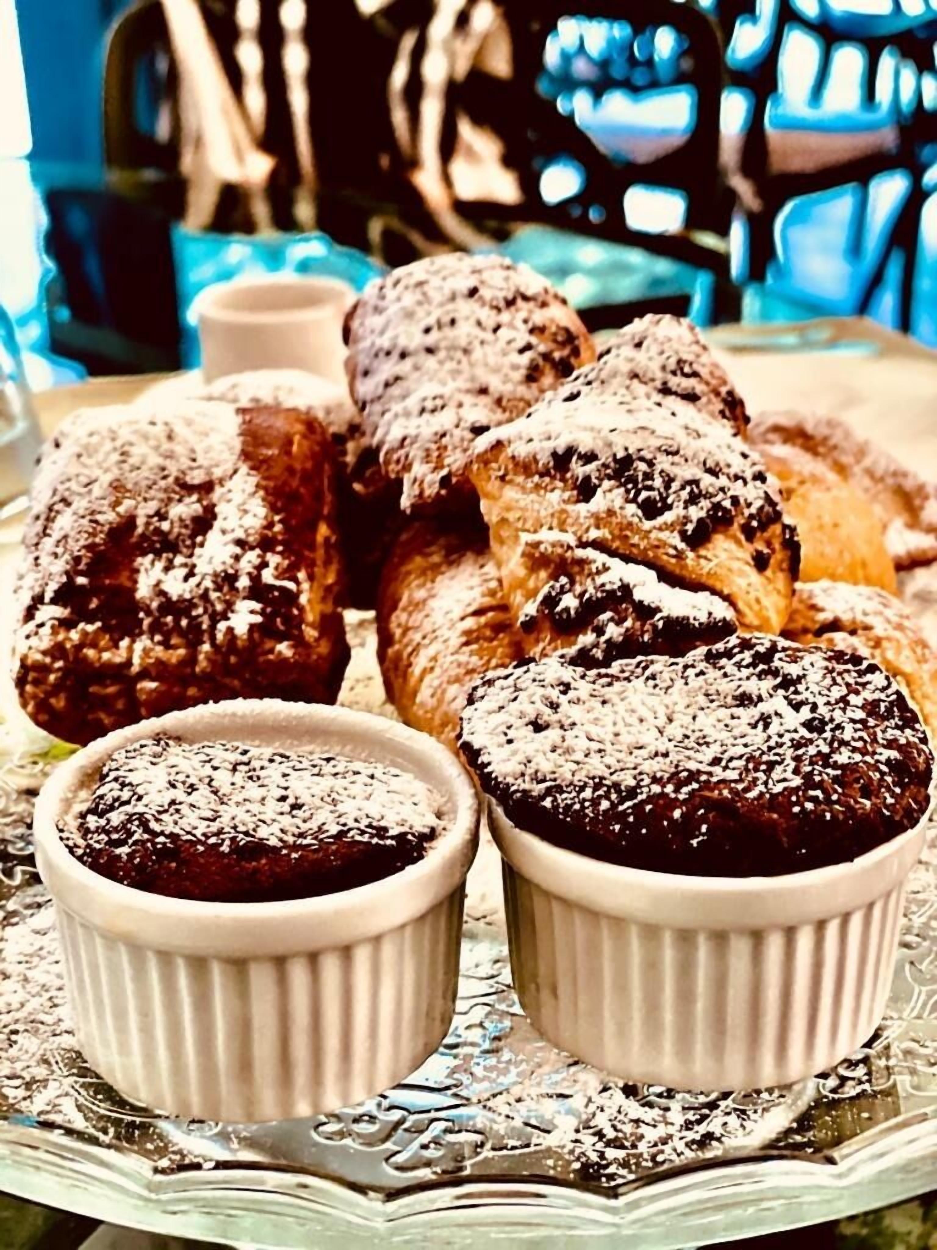 A tray of pastries and desserts, including chocolate-covered items and a small bowl of chocolate sauce.