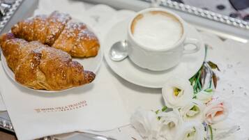 Ein Tablett mit Croissants, einer Kaffeetasse und einem Blumenstrauß.