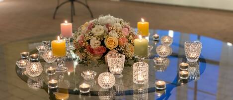 A round glass table with candles and a floral centerpiece.