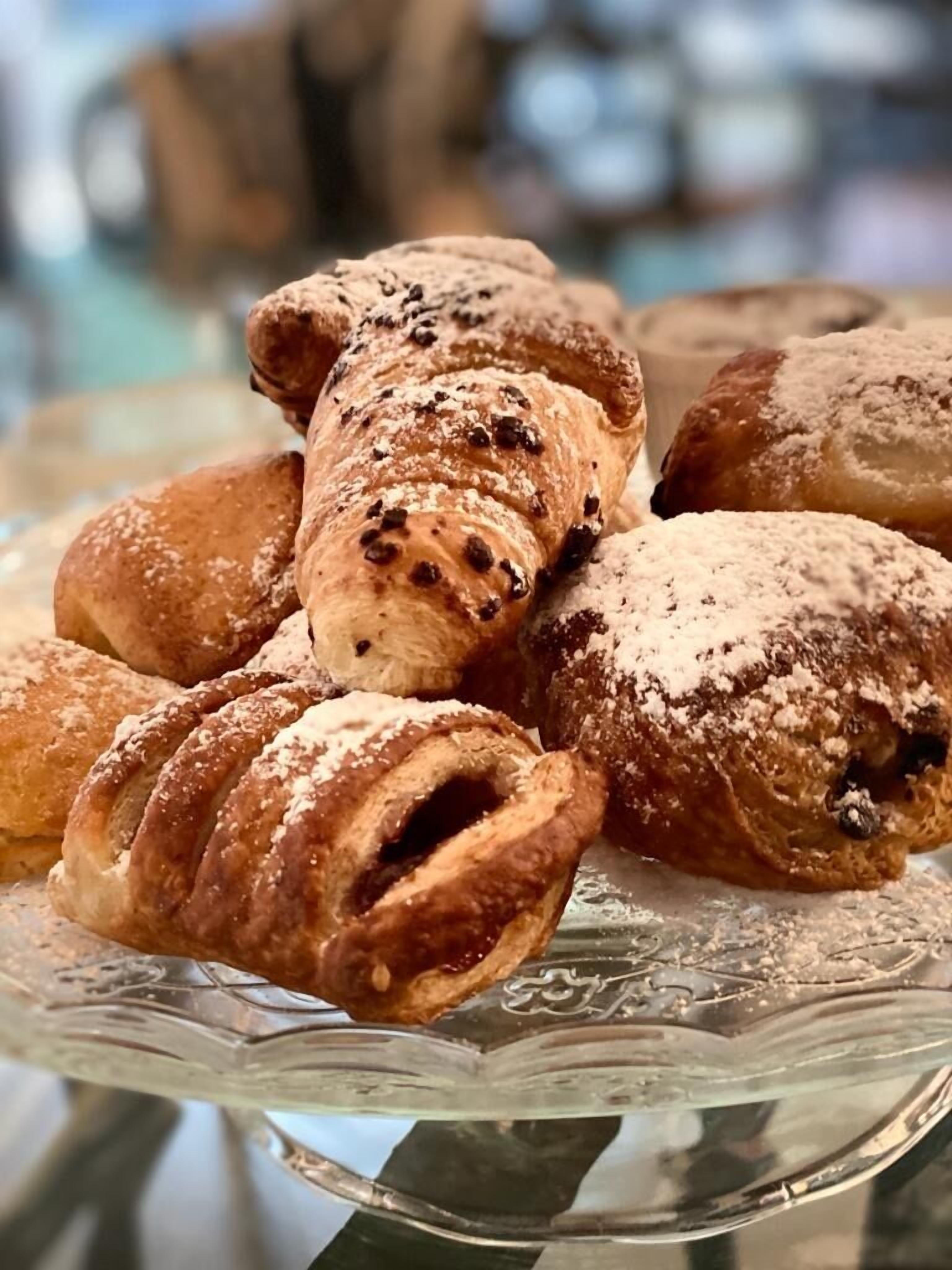A glass display case with various pastries, including croissants and other baked goods.