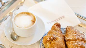 Un vassoio con una tazza di caffè, un cucchiaino e due pasticcini su un tavolo.