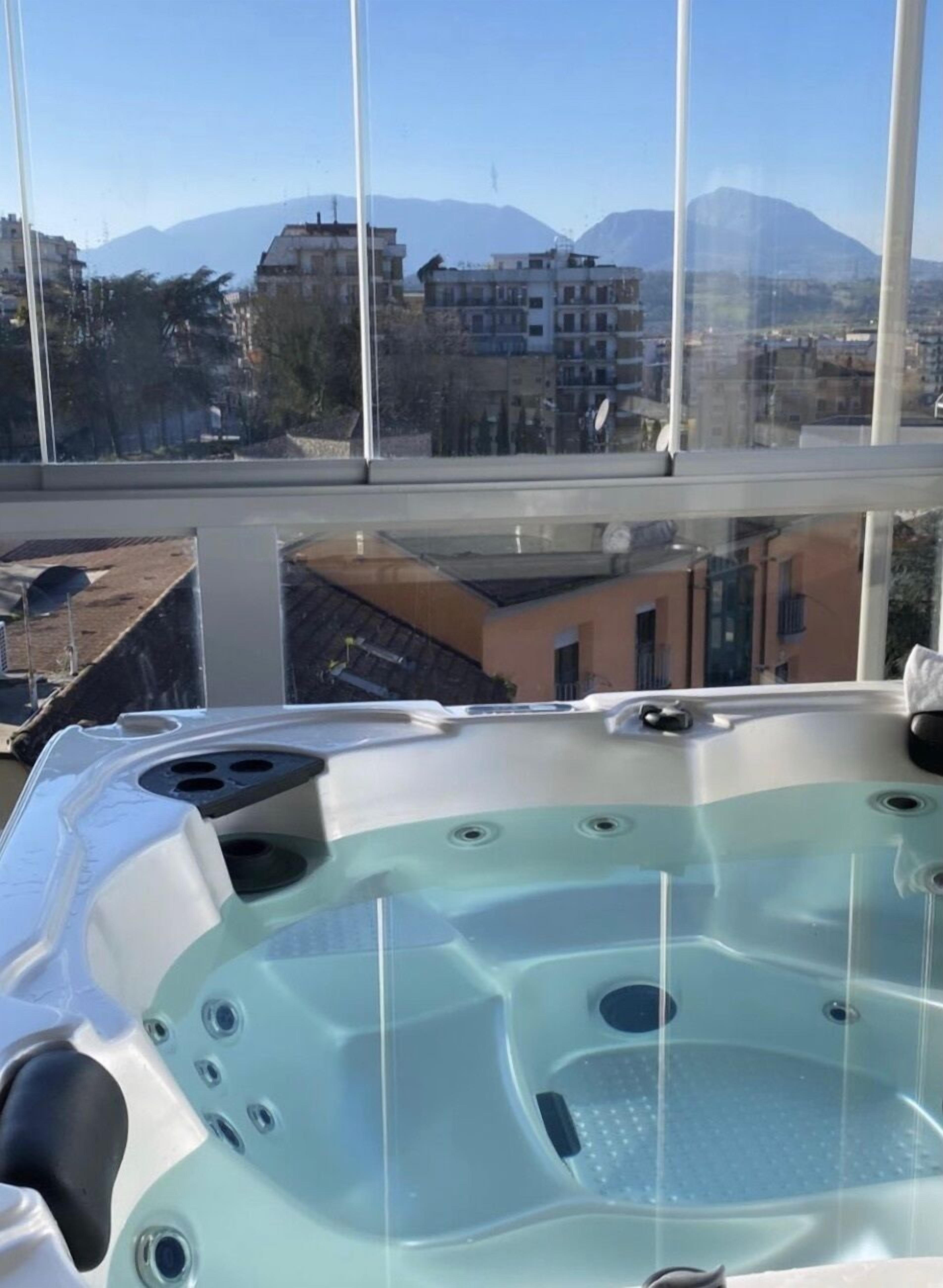 Ein Whirlpool mit freiem Blick auf Gebäude und Berge im Hintergrund.