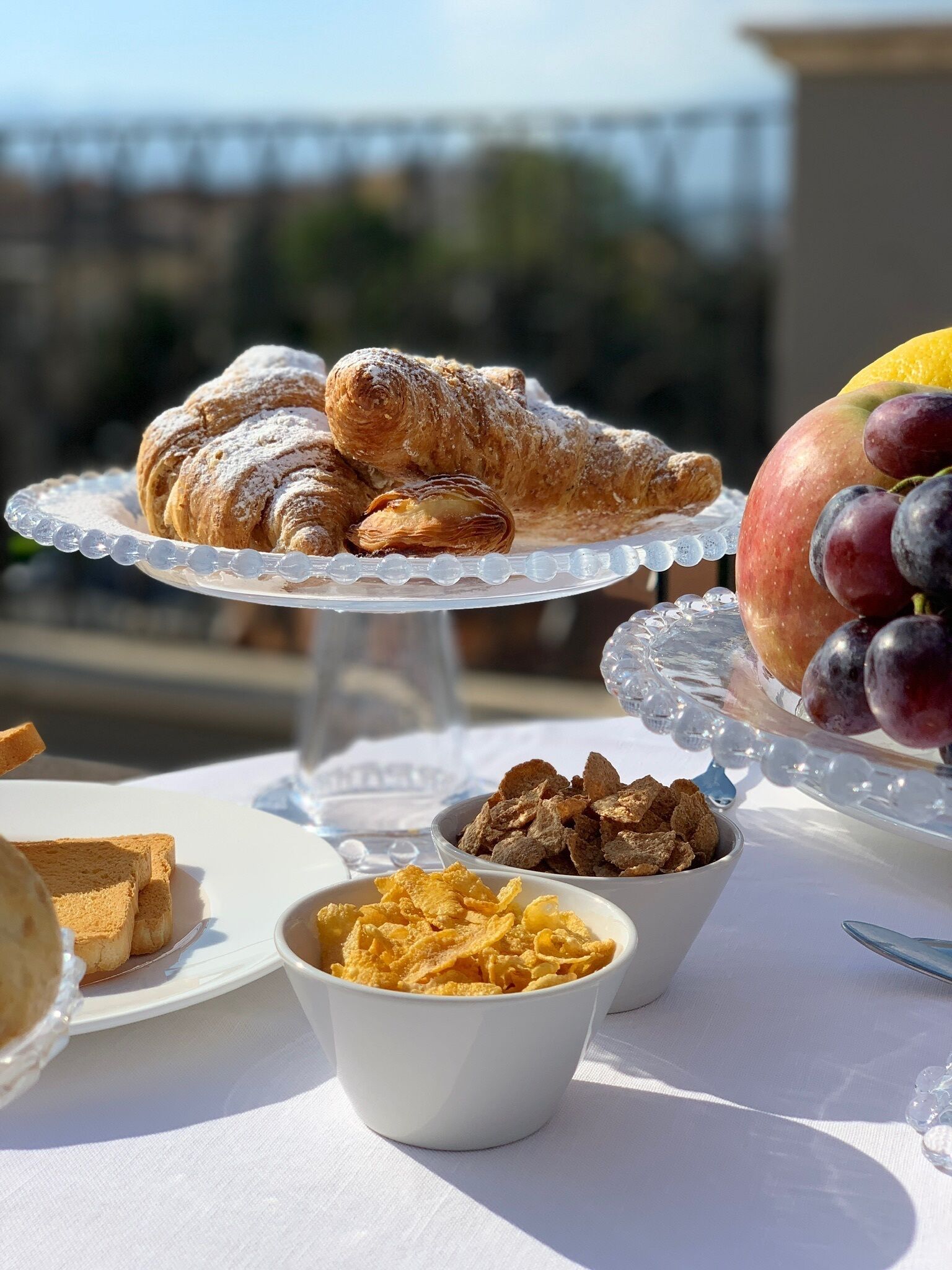 A table with pastries, fruits, and cereal.