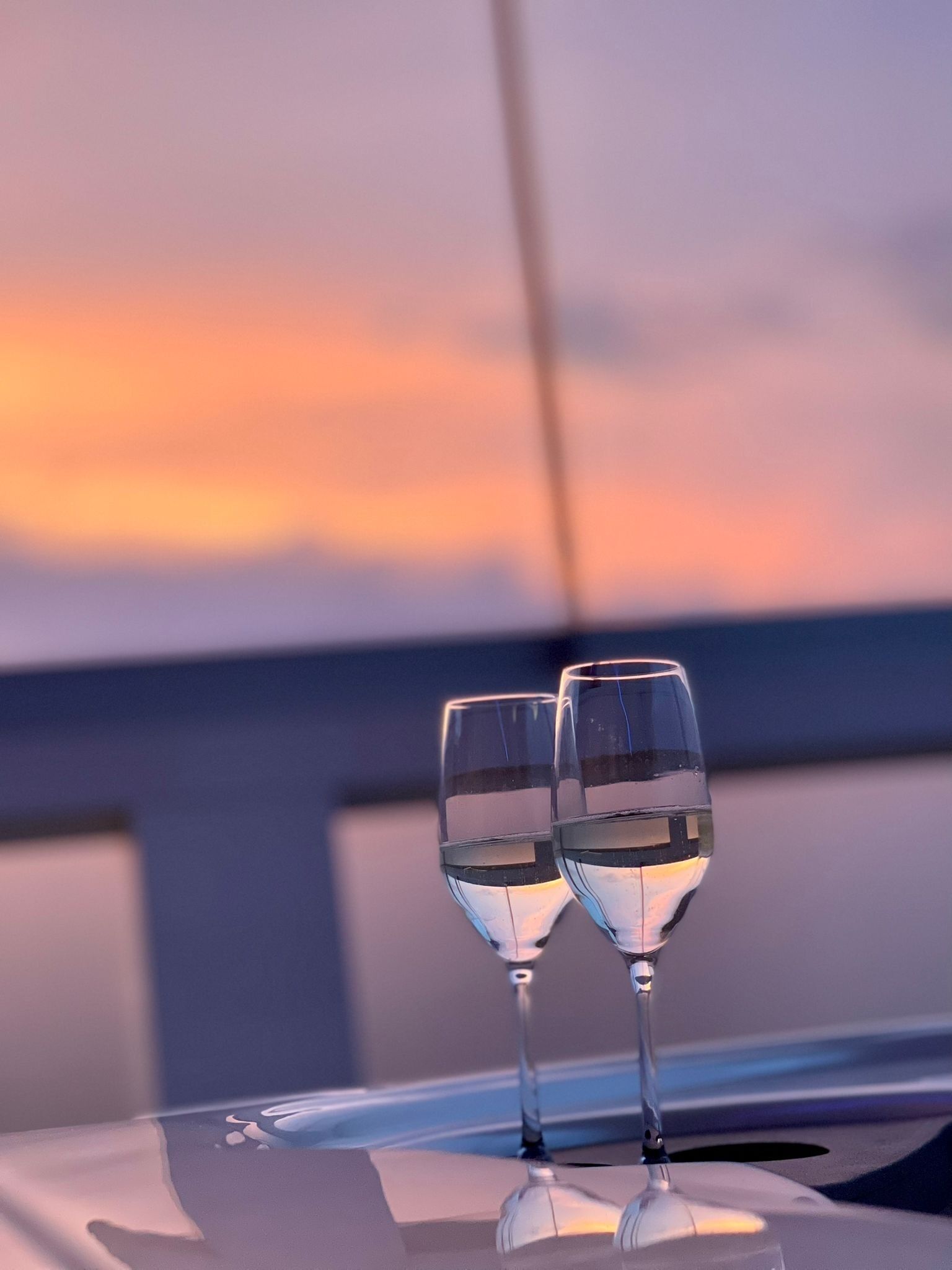 Two glasses of water on a table with a sunset view.