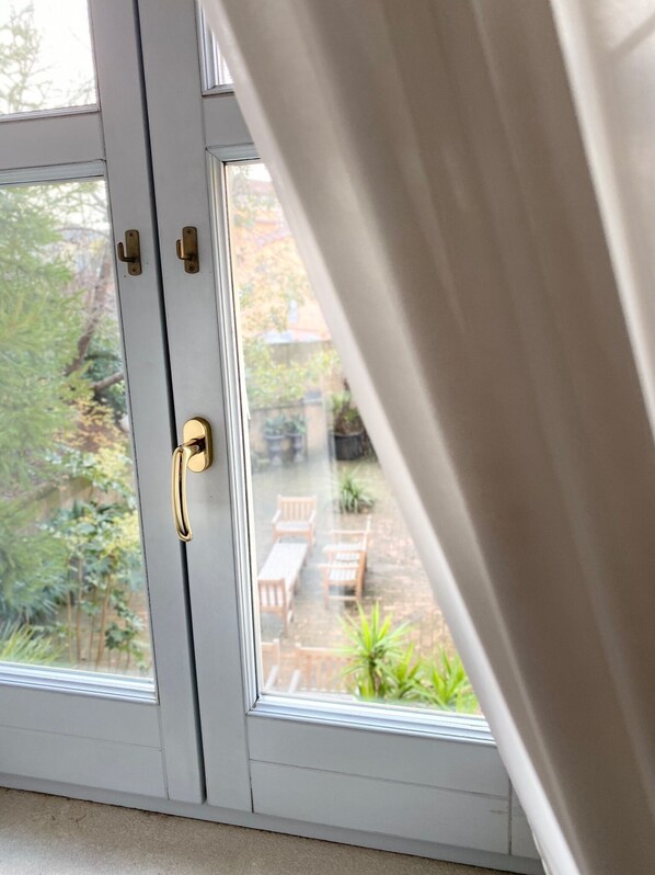 A door with a brass handle and a view of an outdoor patio with wooden furniture and plants. - Hotel Villa Traiano (Benevento)