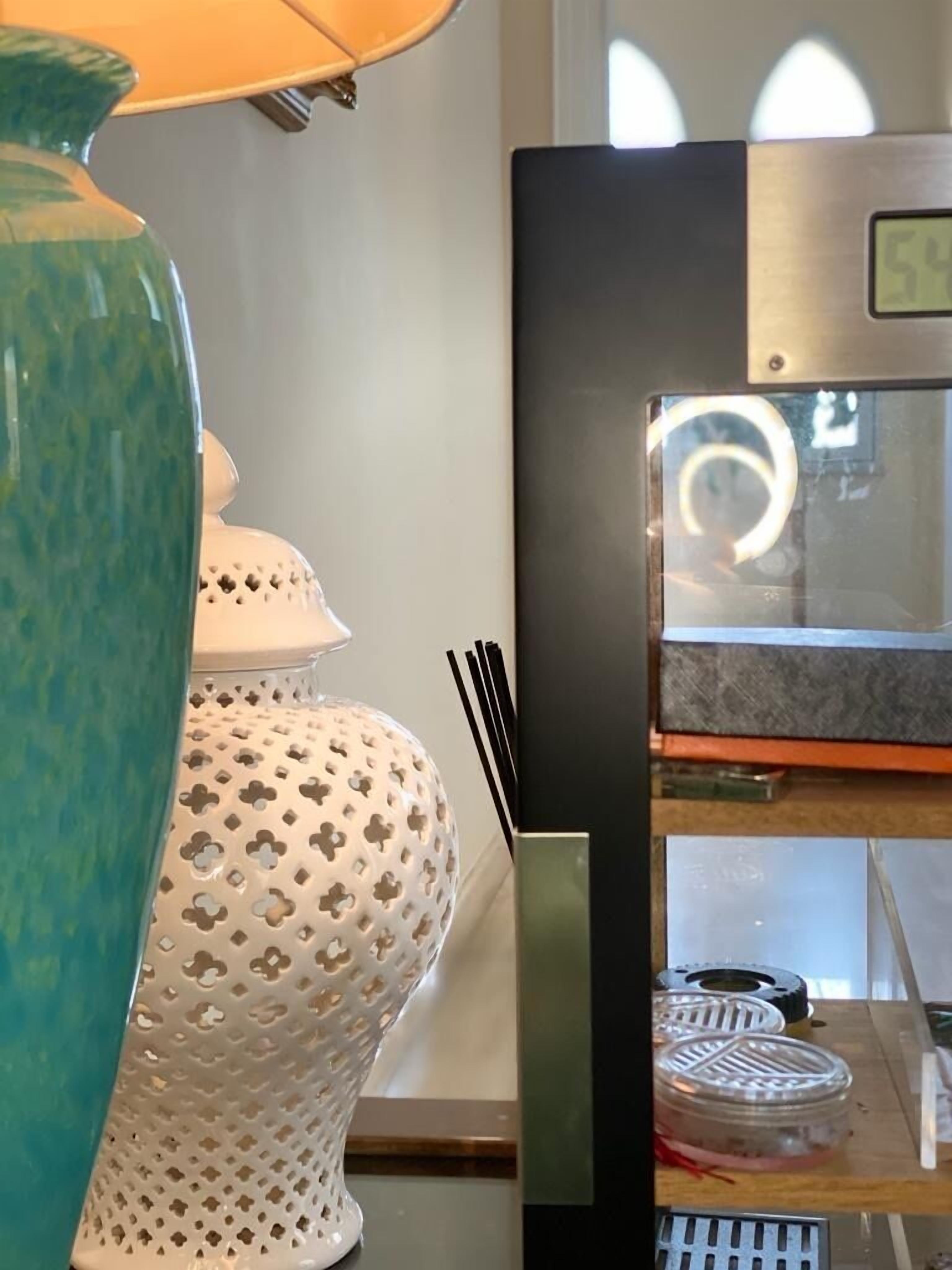 Eine blaustichige Vase, ein weißer Keramiktopf mit Deckel und ein schwarzer Kühlschrank mit Digitalanzeige.