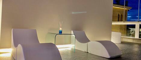 Un área de descanso moderna con dos sillones blancos y una mesita con un jarrón azul.