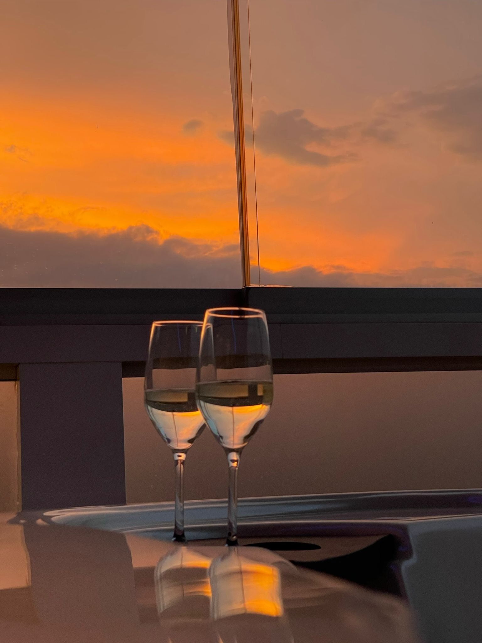 Two glasses of white wine on a table with a sunset view.