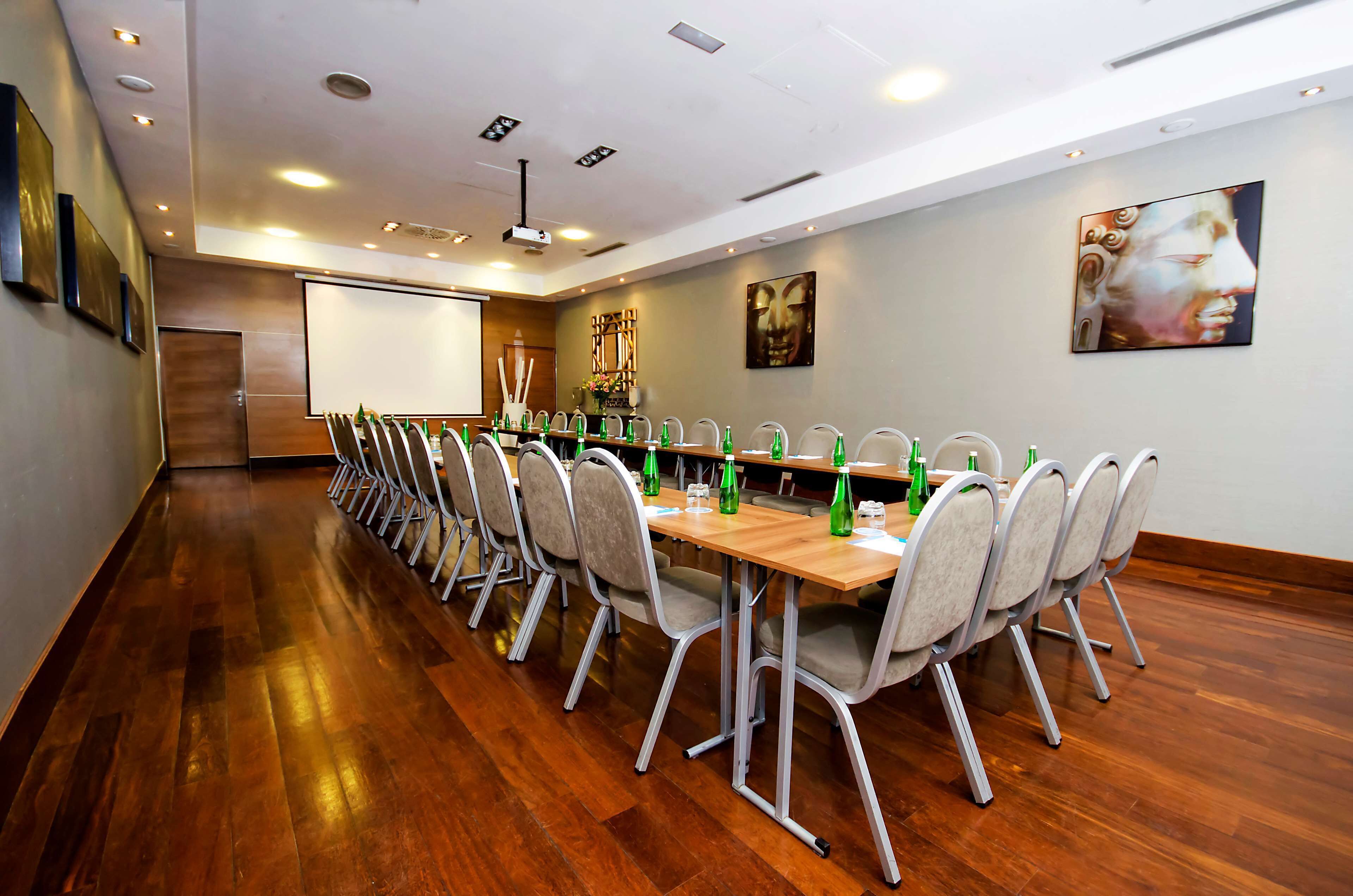 A conference room with a long table, chairs, and a projector screen.