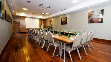 A conference room with a long table, chairs, and a projector screen.
