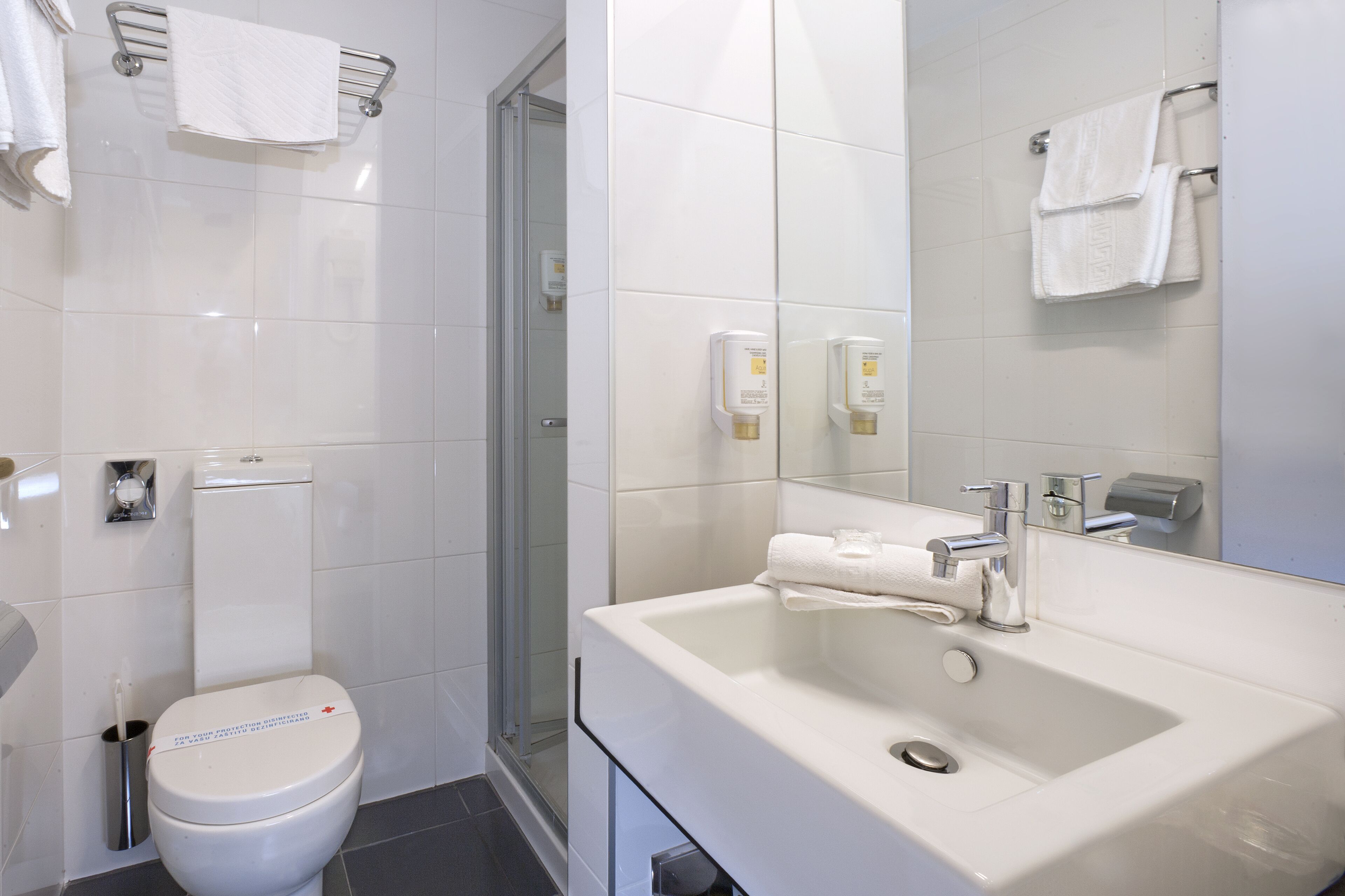 A modern bathroom with a toilet, sink, and glass shower enclosure.