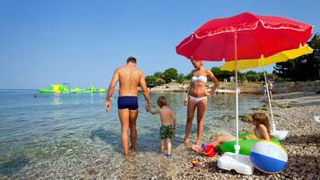 En la playa, sillas reclinables de playa, sombrillas, vóleibol de playa