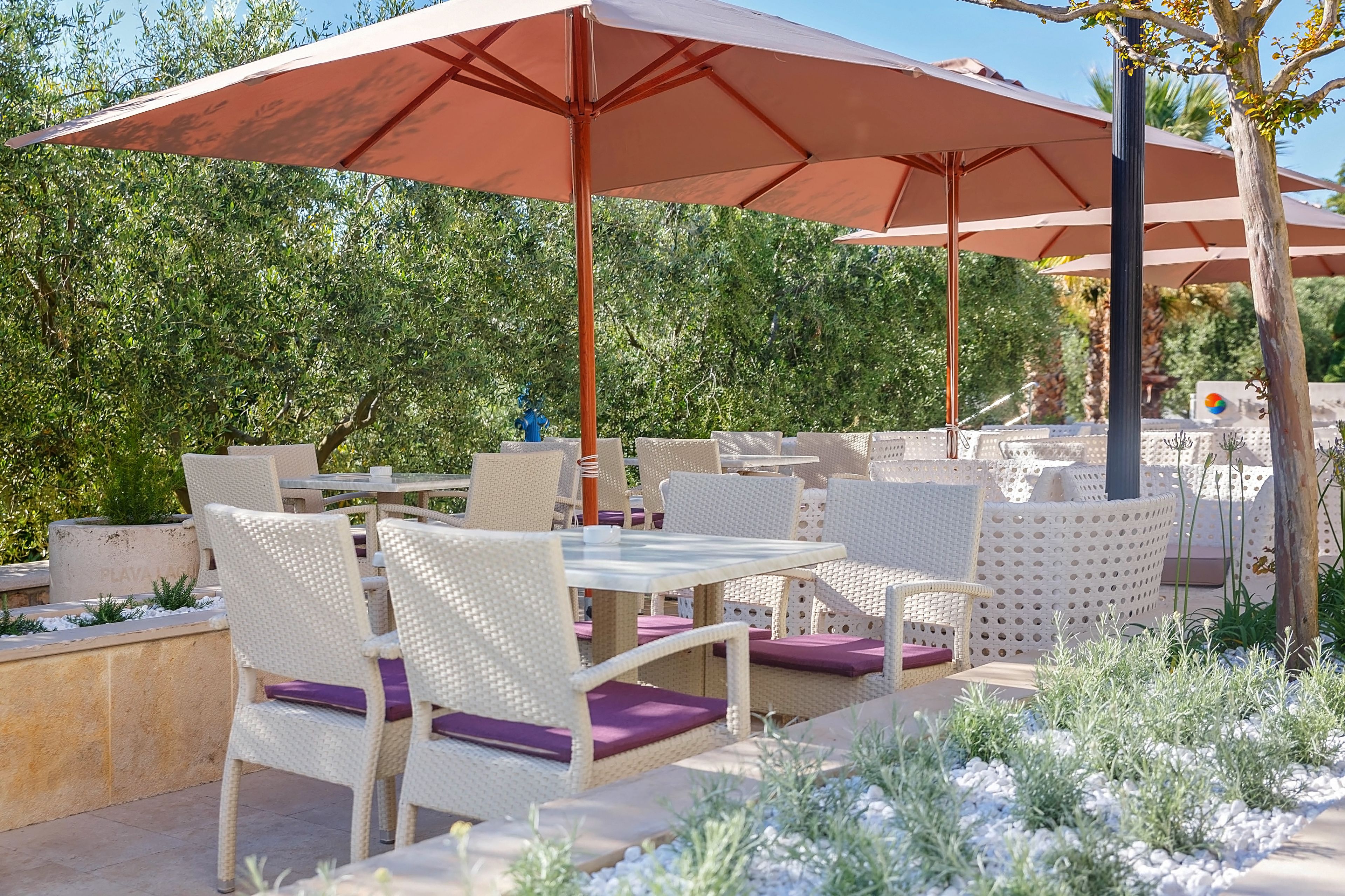 An outdoor patio with wicker furniture, tables, and large umbrellas.