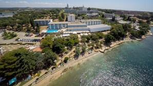 Vista aérea de un hotel costero con varias edificaciones, una piscina y una zona de playa.