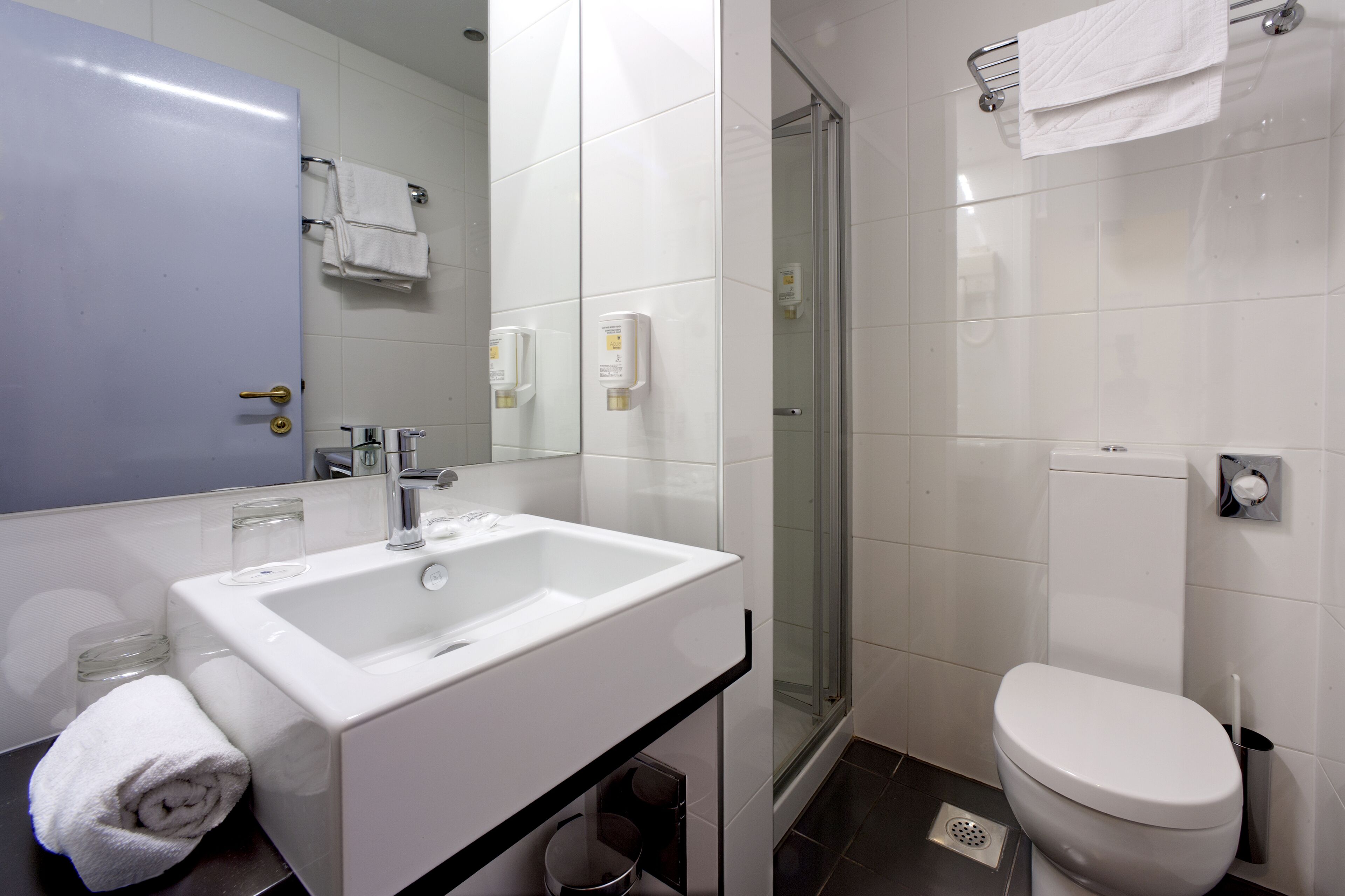 A modern bathroom with a white sink, mirror, and toilet.