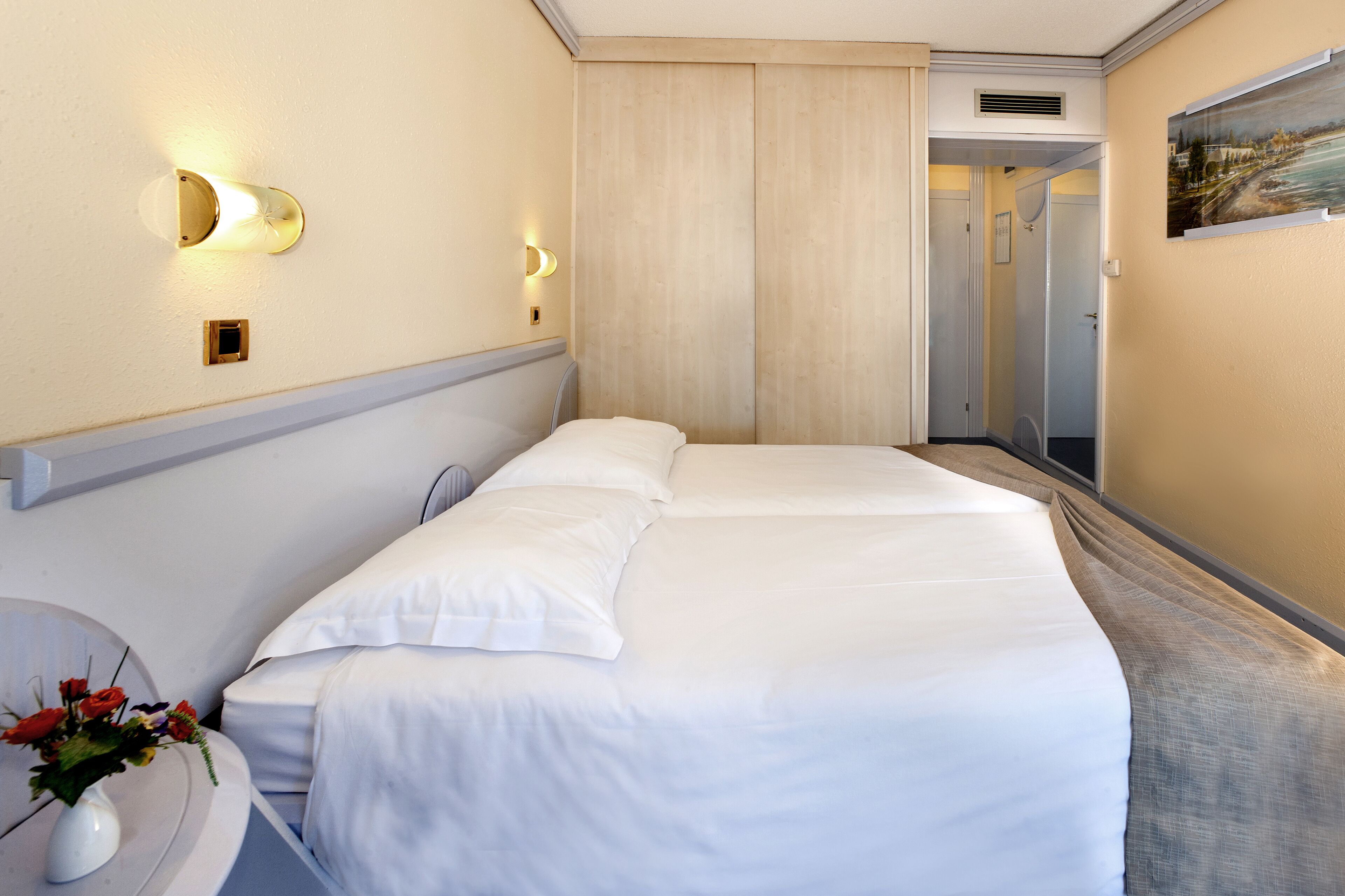 Ein Hotelzimmer mit einem großen Bett, Nachttischen und einem Bild an der Wand.