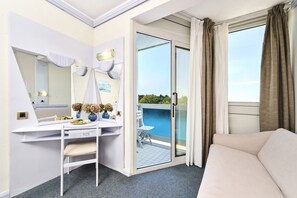 A hotel room with a balcony, a desk with a chair, a bed, and a large mirror.