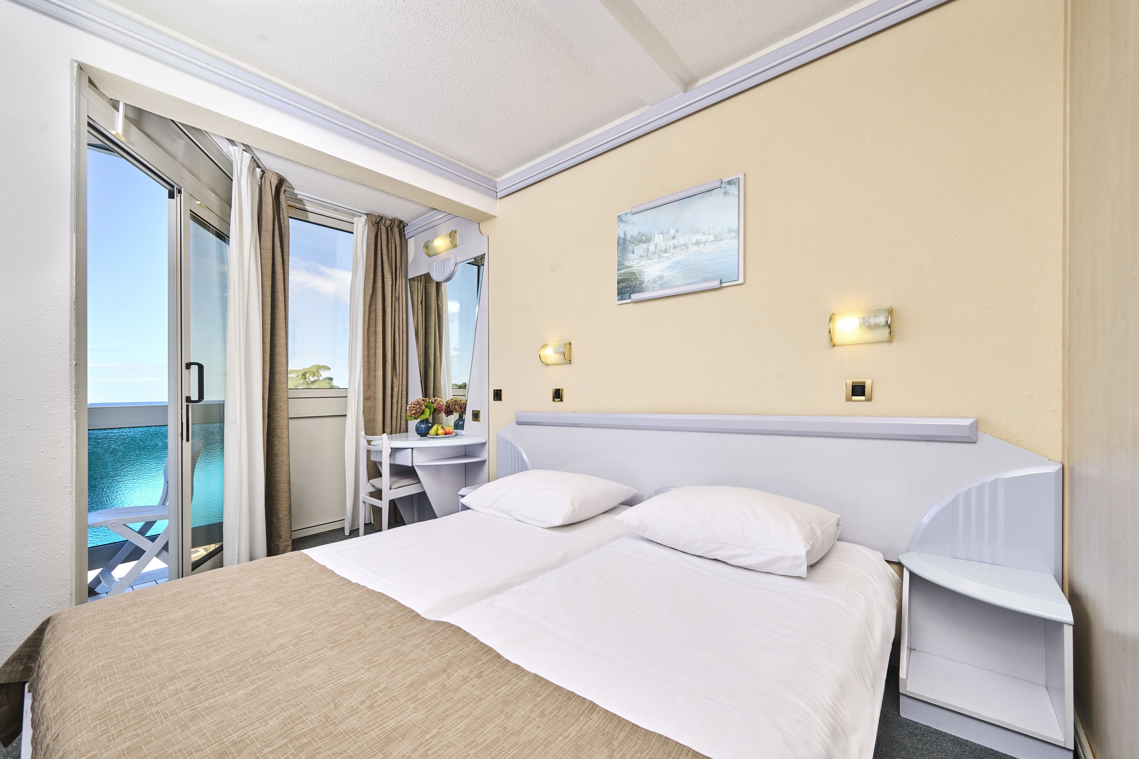 Habitación de hotel con cama, escritorio, silla y vista al mar.