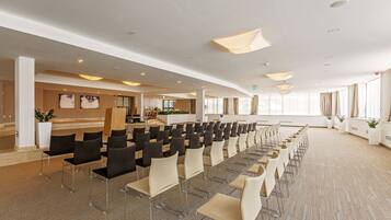 A conference room with rows of chairs, a reception area, and large windows.