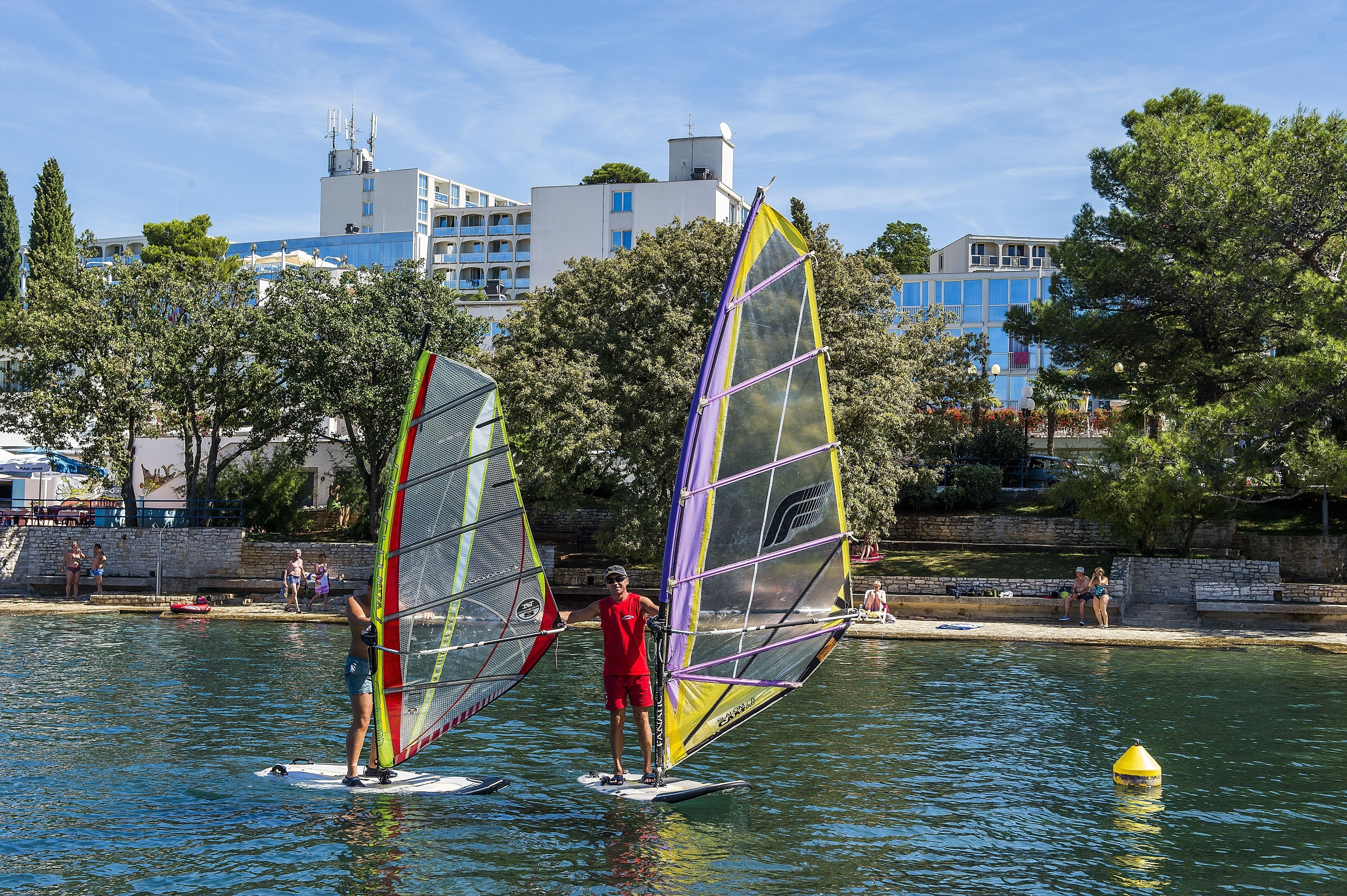 Een waterkant met windsurfers.