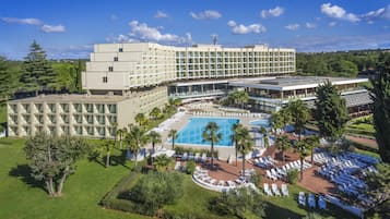 Un hotel con piscina, tumbonas y un jardín ajardinado.