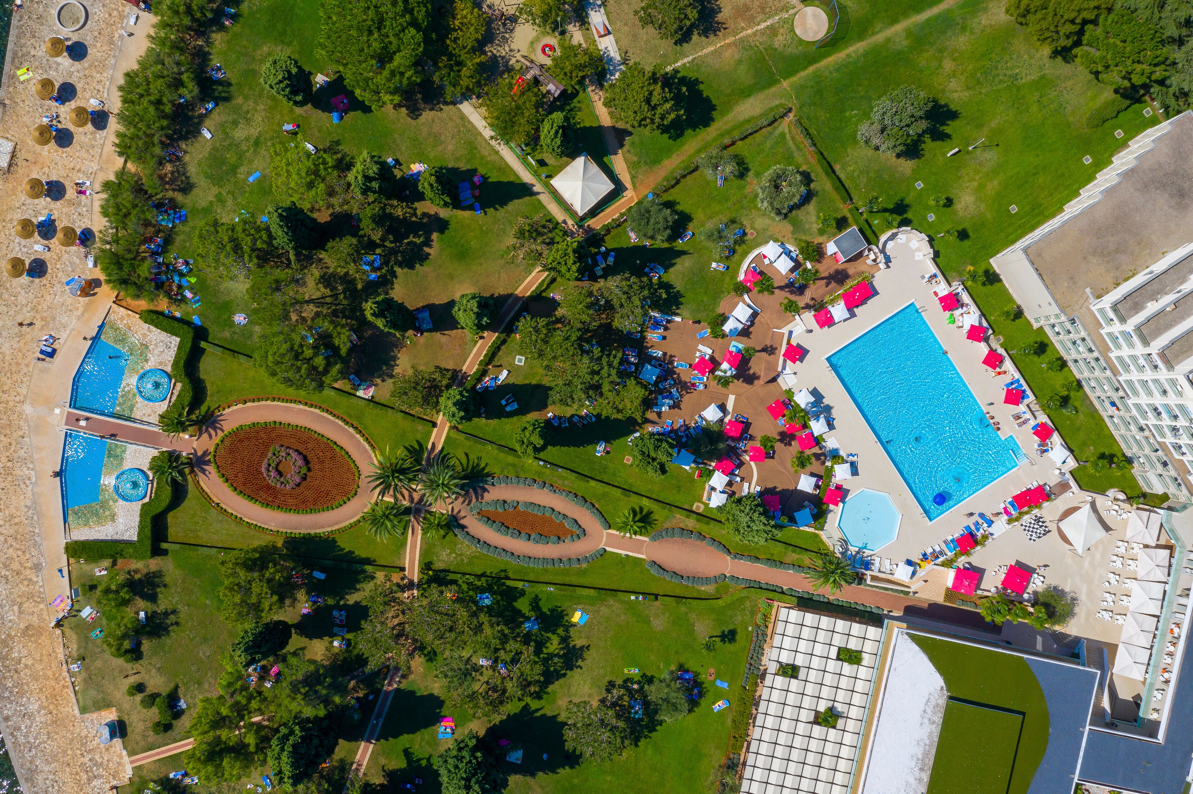 An aerial view of a resort with multiple swimming pools, a large central pool, and a variety of outdoor seating areas.