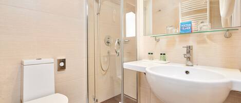 A modern bathroom with a glass shower enclosure, a white sink, and a toilet.