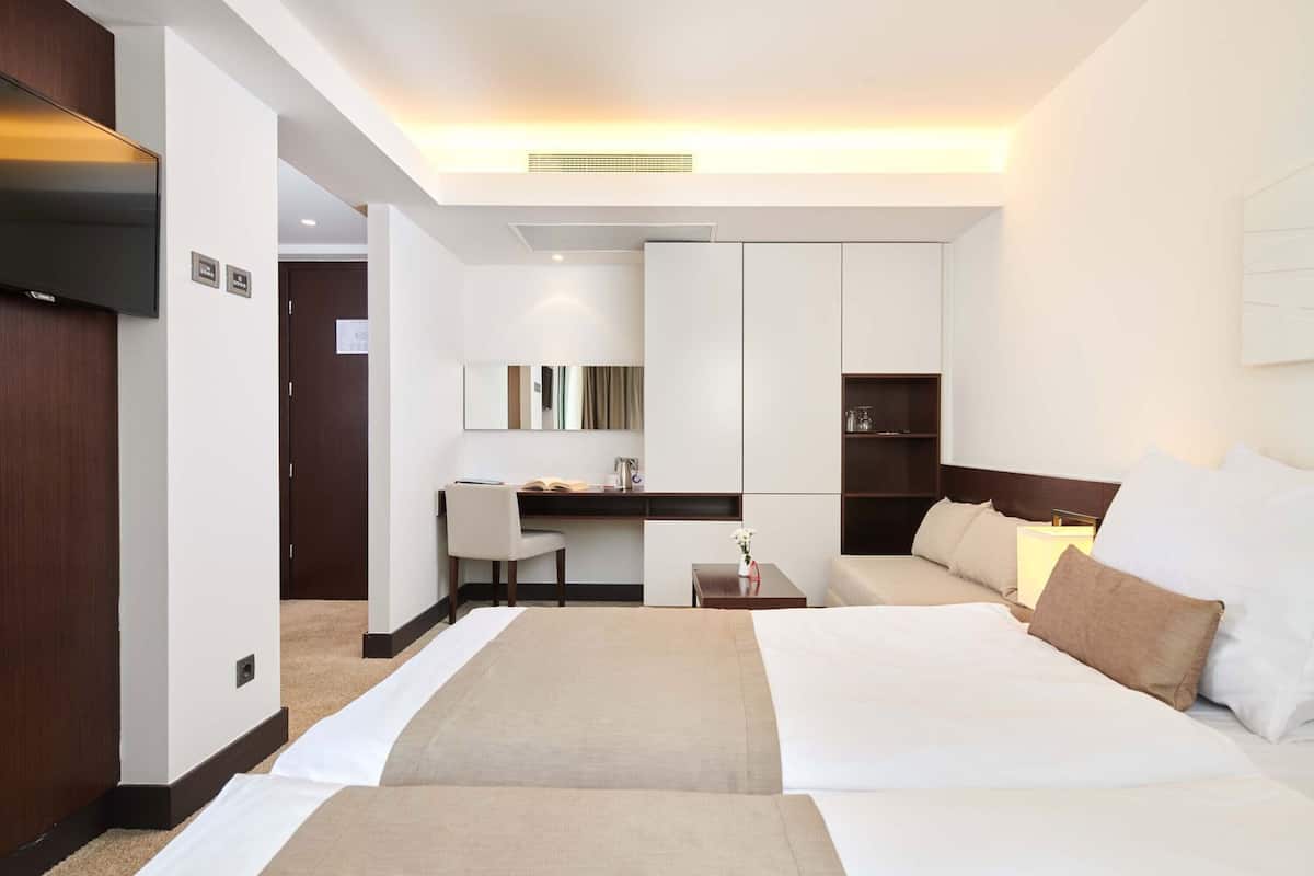 A hotel room with a bed, a desk, a chair, a TV, and a wardrobe.