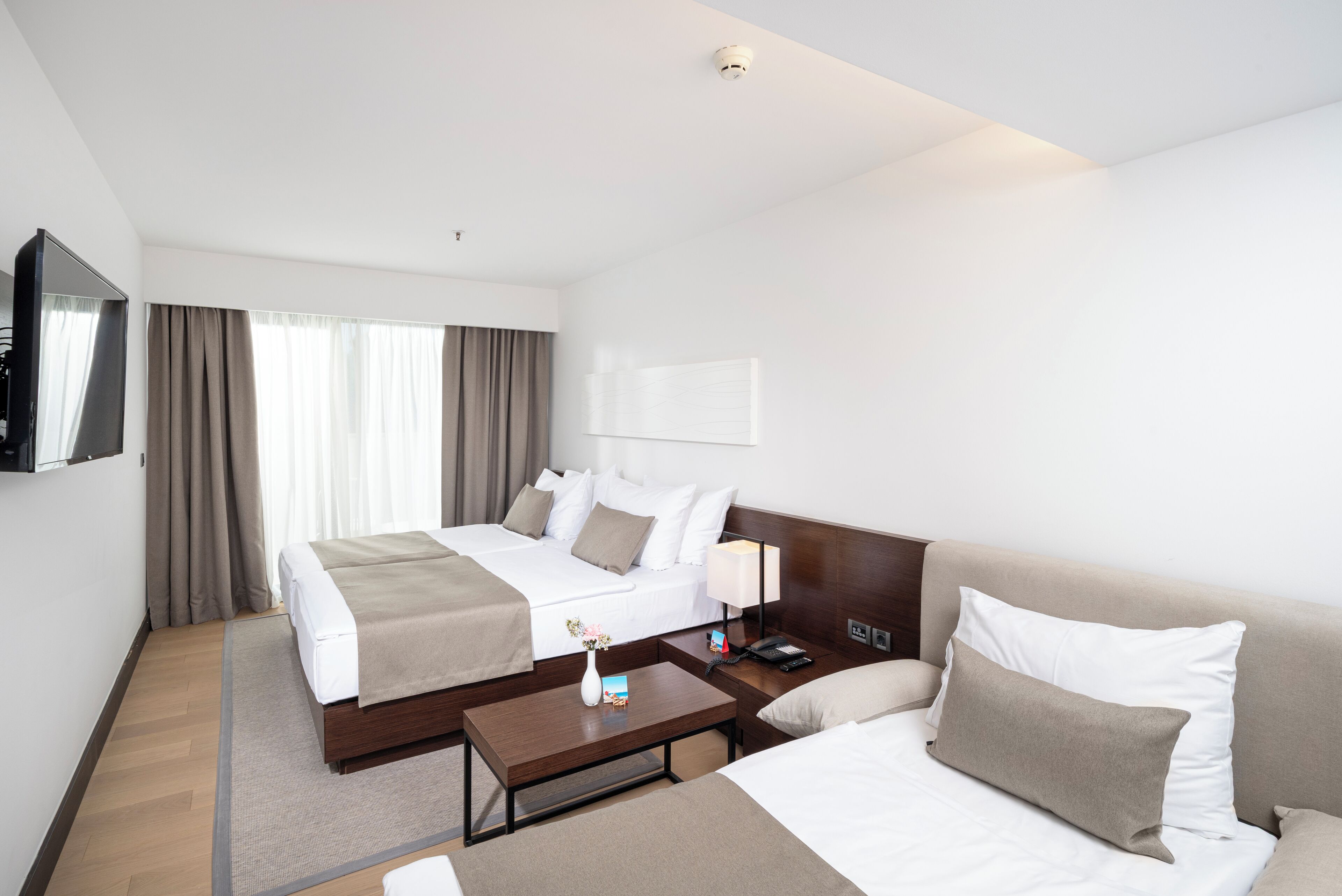 Habitación de hotel con dos camas, un televisor de pantalla plana, una mesita de noche y una lámpara.