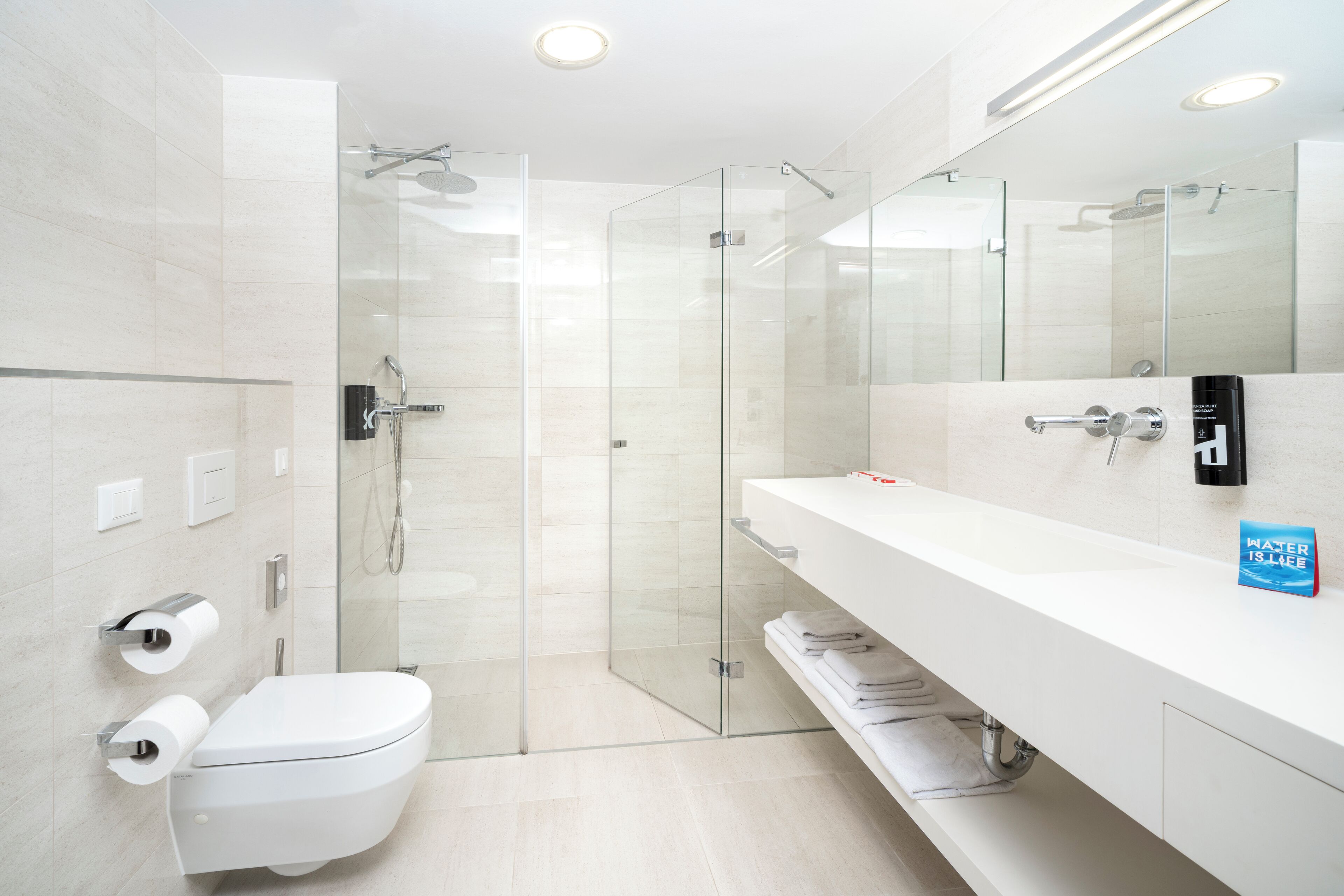 A modern bathroom with a glass-enclosed shower, a white sink, and a toilet.