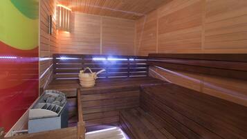 A sauna with wooden benches, a bucket, and a stone-filled container.