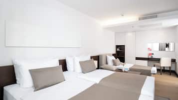 A modern hotel room with two beds, a desk, and a large mirror.