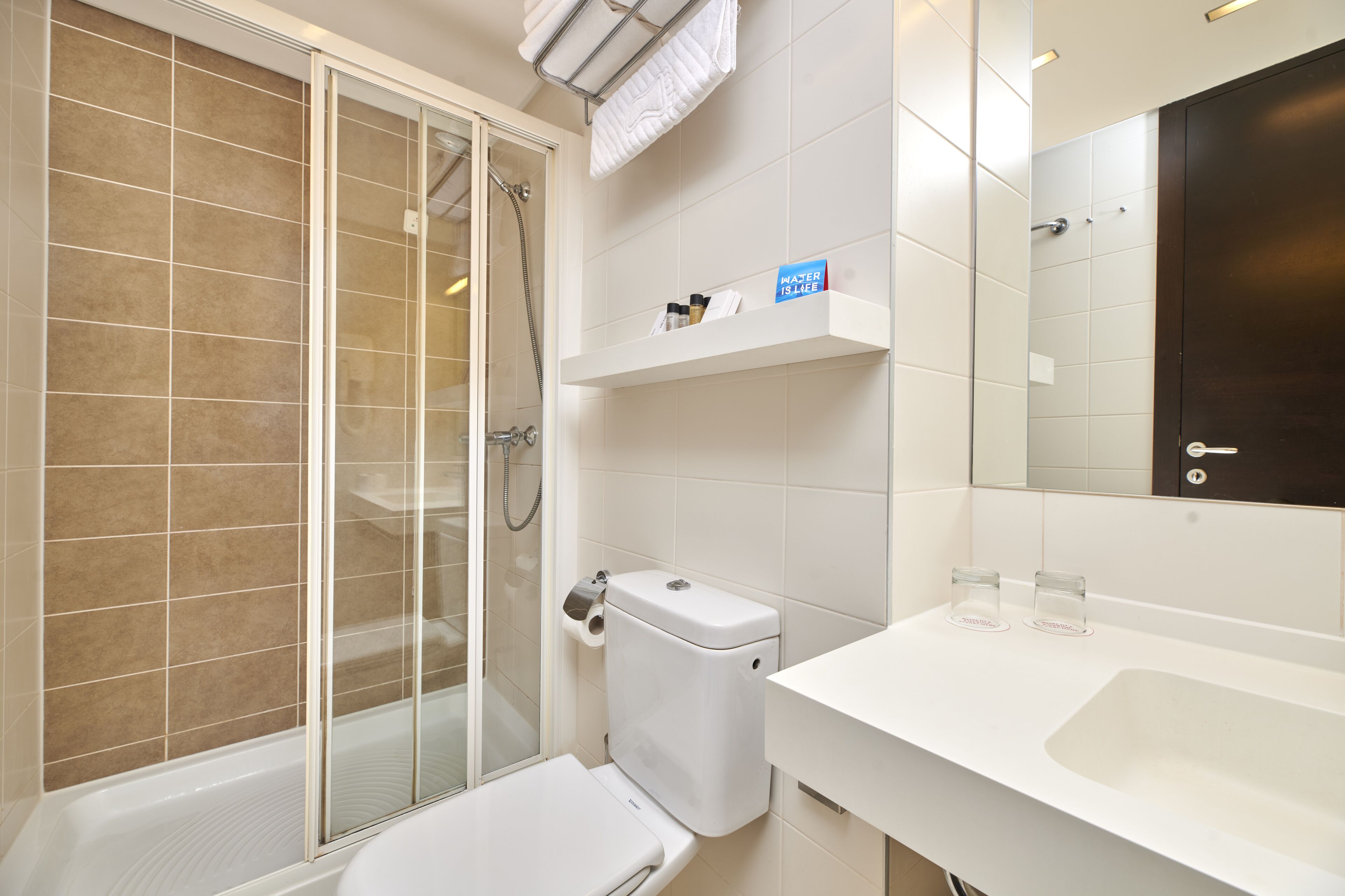 A modern bathroom with a glass-enclosed shower, a toilet, a sink, and a mirror.