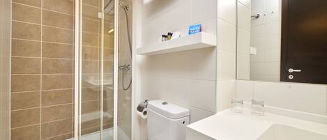 A modern bathroom with a glass-enclosed shower, a toilet, a sink, and a mirror.