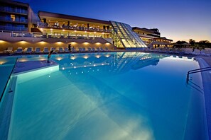 A swimming pool with lounge chairs and a modern building with a glass facade in the background. - Hotel Molindrio Plava Laguna (Porec)