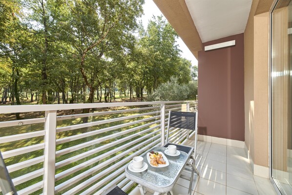 A balcony with a table set for two, a plate of food, and a cup. - Hotel Molindrio Plava Laguna (Porec)