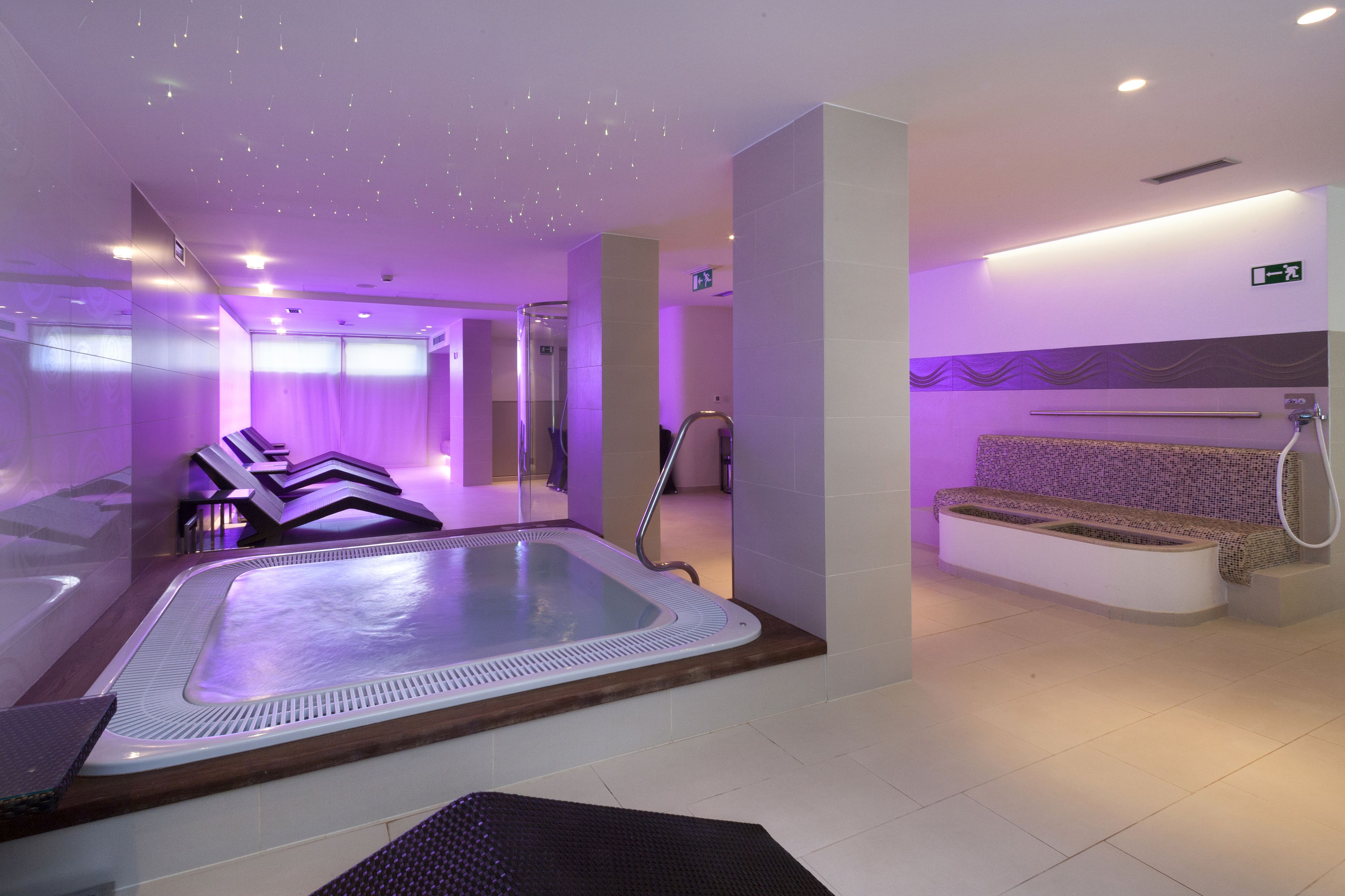 Un moderno espacio de spa con hidromasaje, zona de estar y ducha.