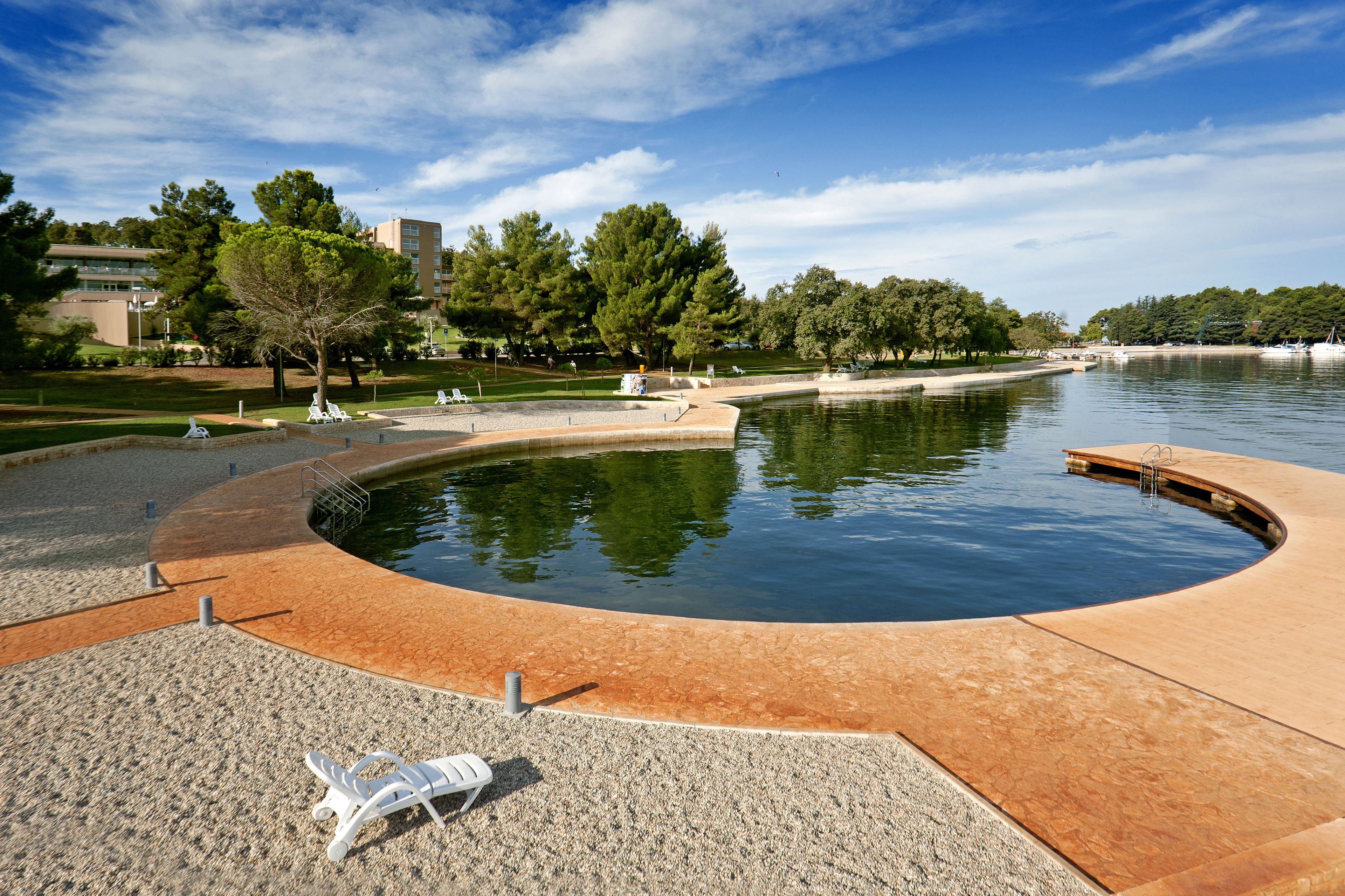 A landscaped area with a circular water feature, seating, and trees.