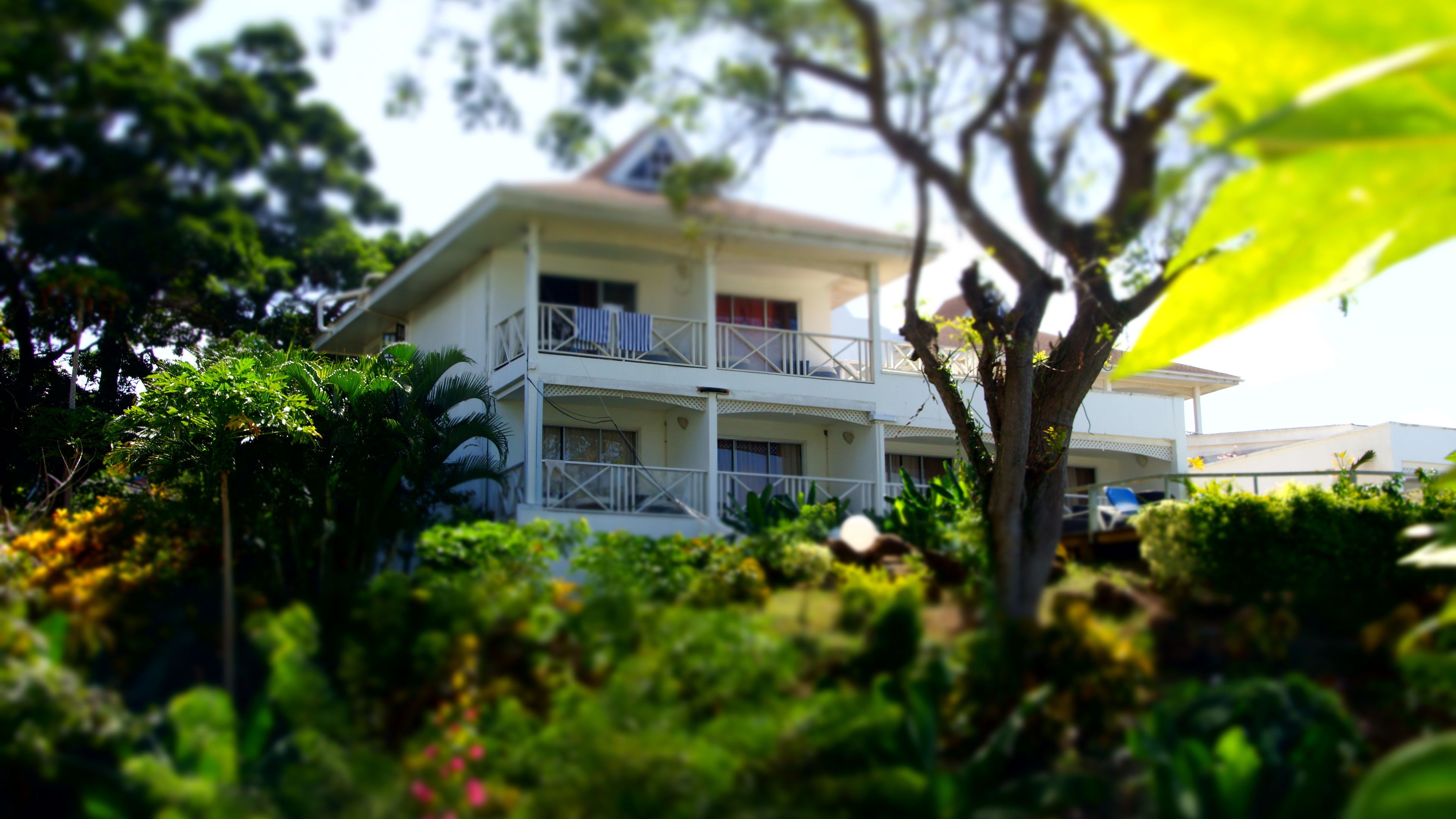 A two-story building with balconies, surrounded by lush greenery.