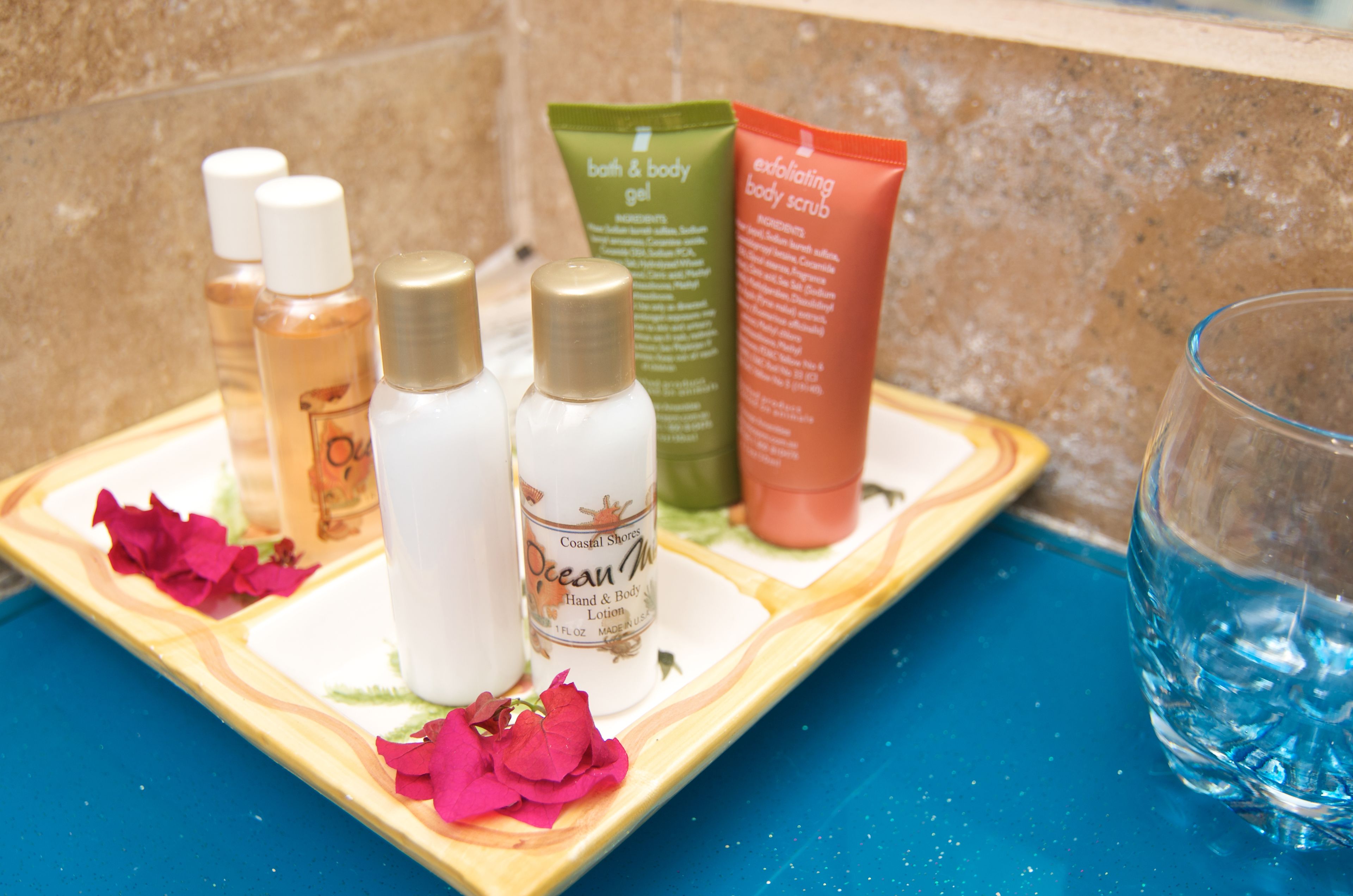 A tray with various bath and body products, including lotions and scrubs, on a blue countertop.