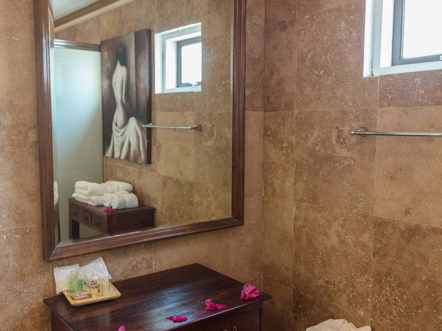 A bathroom with a large mirror, a wooden dresser, and a bench with towels.