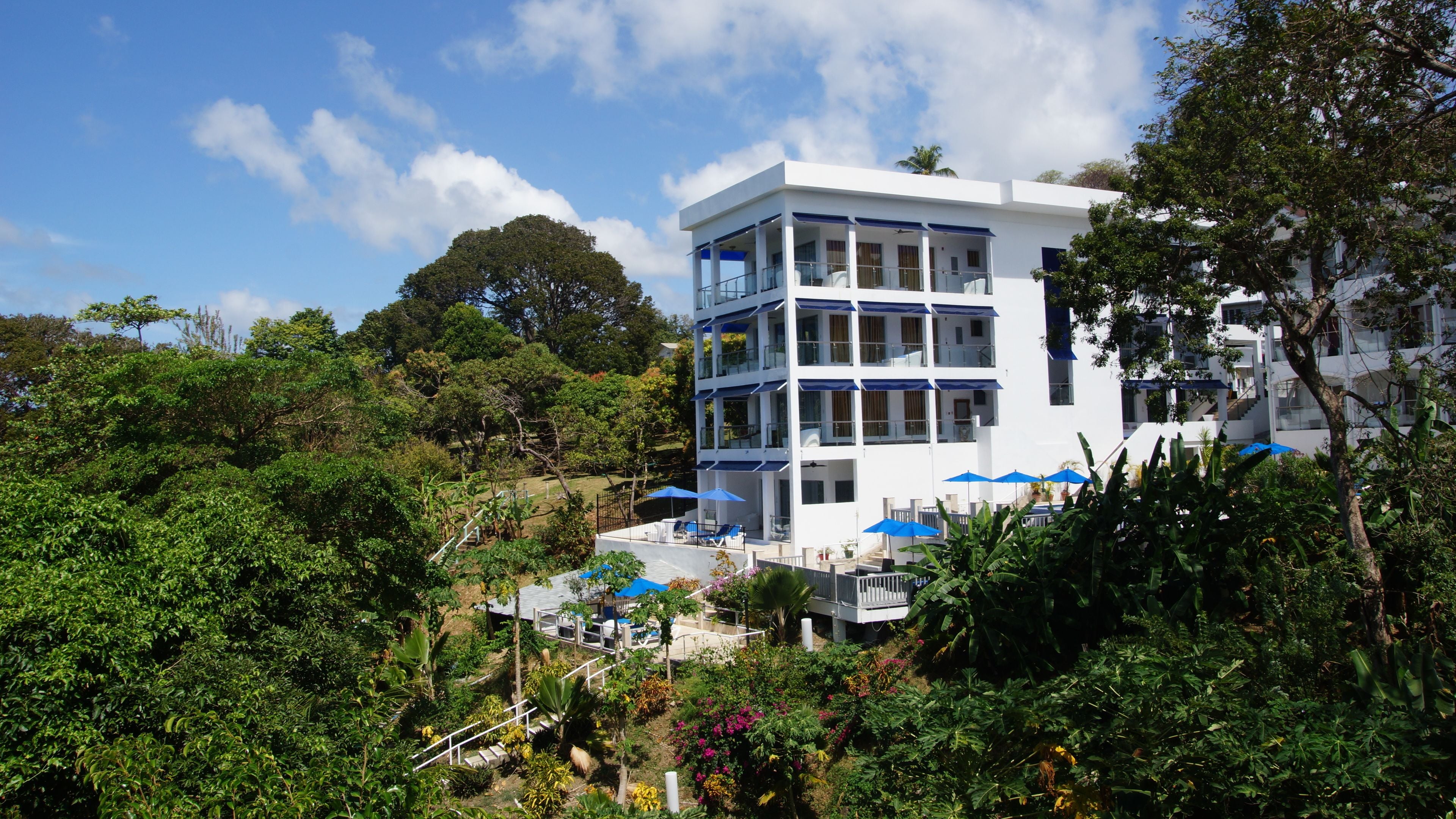 A multi-story hotel with balconies, outdoor seating, and lush greenery.